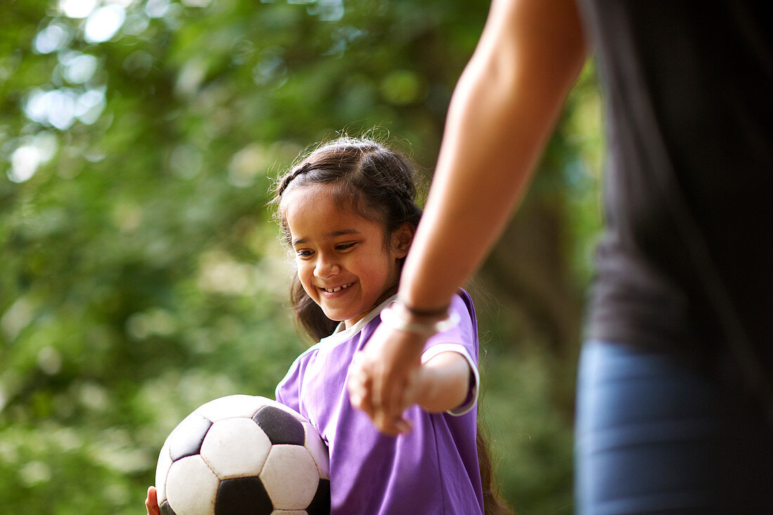 Girl with soccer ball holding hands with mother