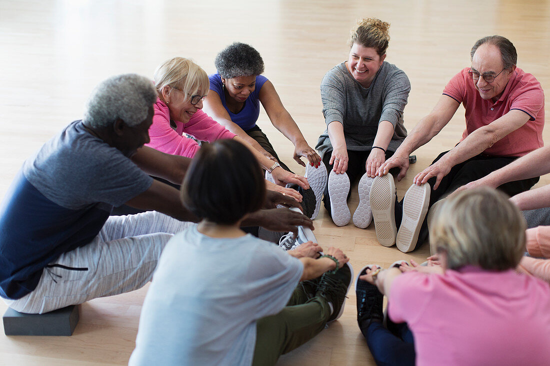 Active seniors stretching legs in circle