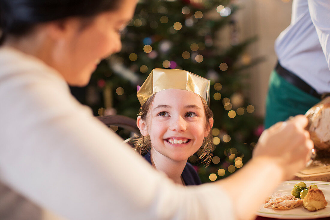 Smiling girl in paper crown at Christmas dinner
