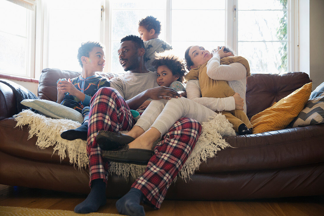 Young family relaxing in pyjamas on sofa