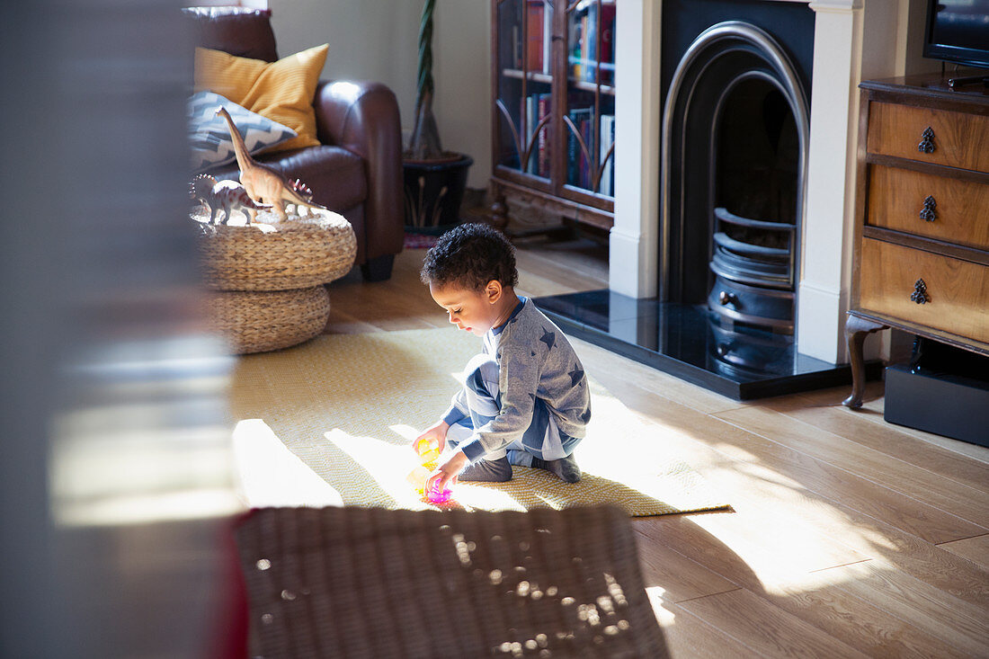 Boy in pyjamas playing with toys on floor