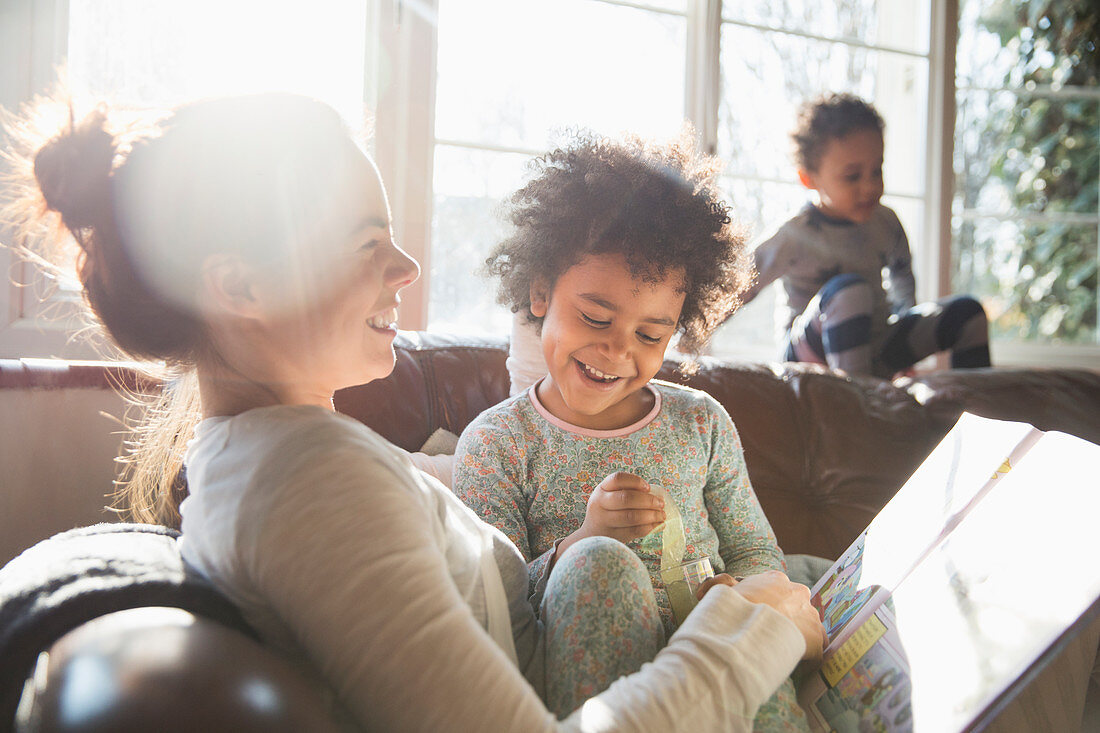 Mother and daughter reading book on sofa