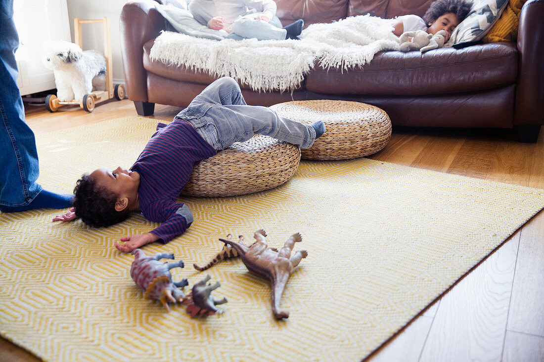 Playful boy with dinosaur toys on floor