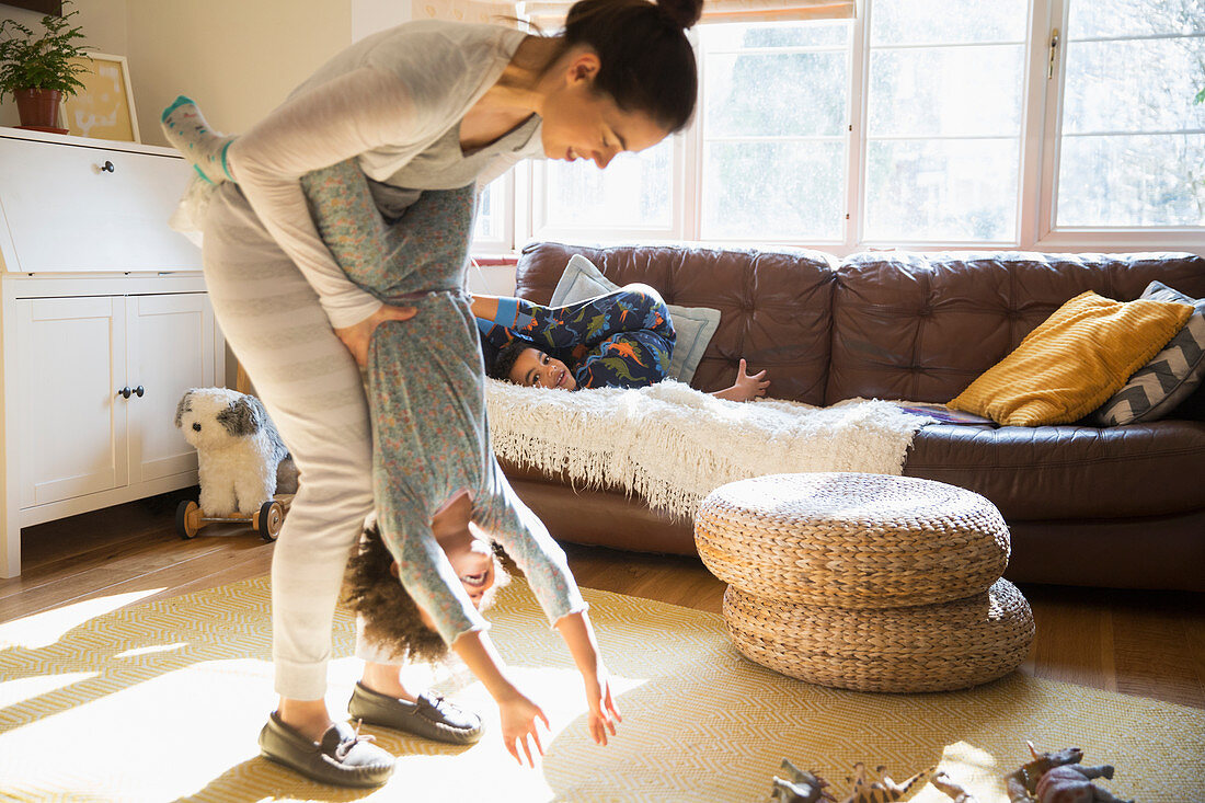 Playful mother and daughter in sunny living room