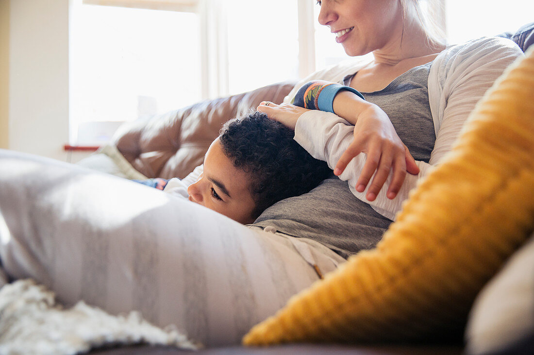 Affectionate mother and son cuddling on sofa