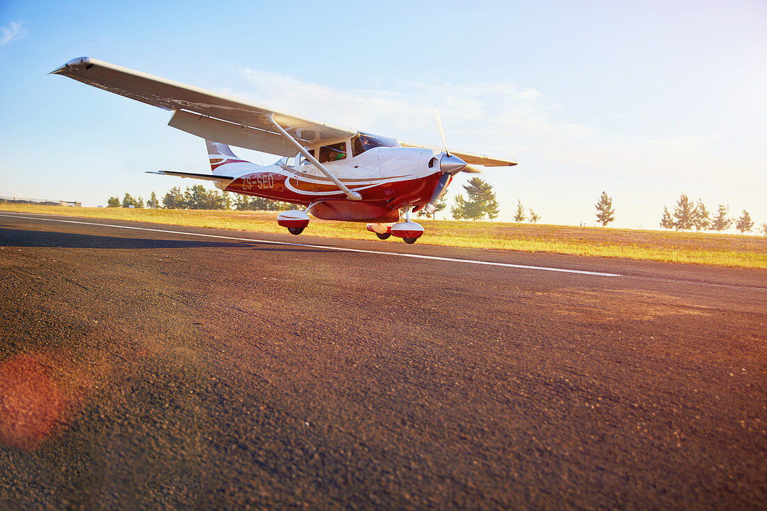 Prop airplane landing on sunny tarmac