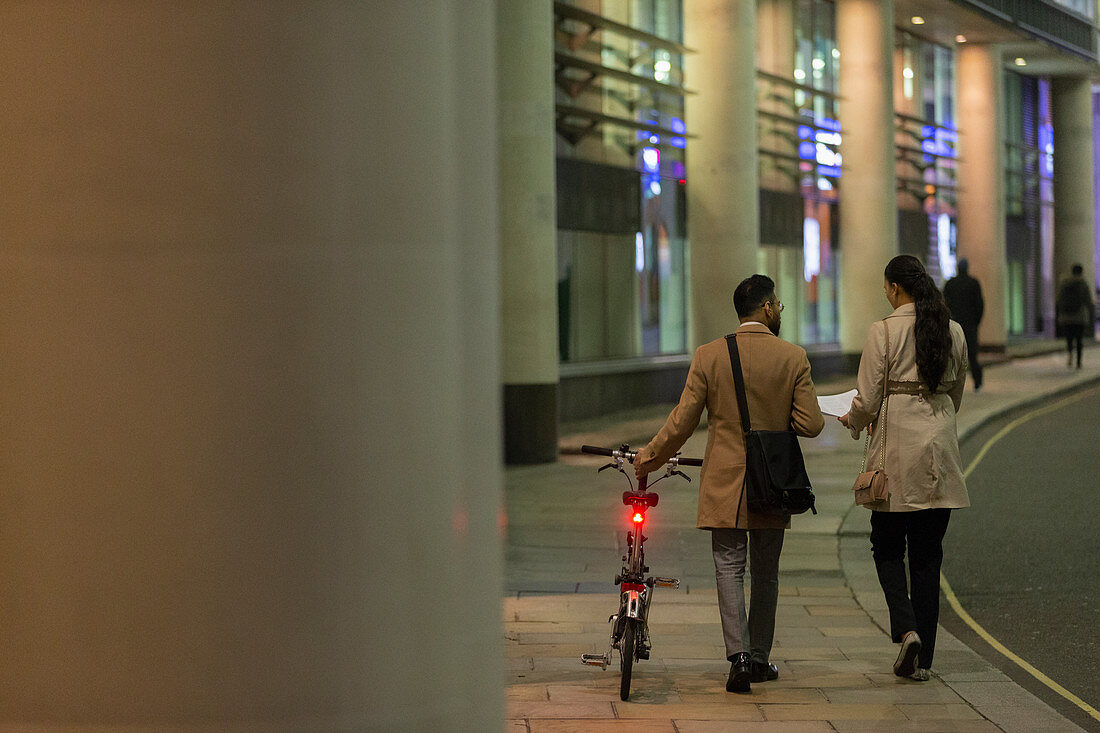 Business people with bicycle walking at night
