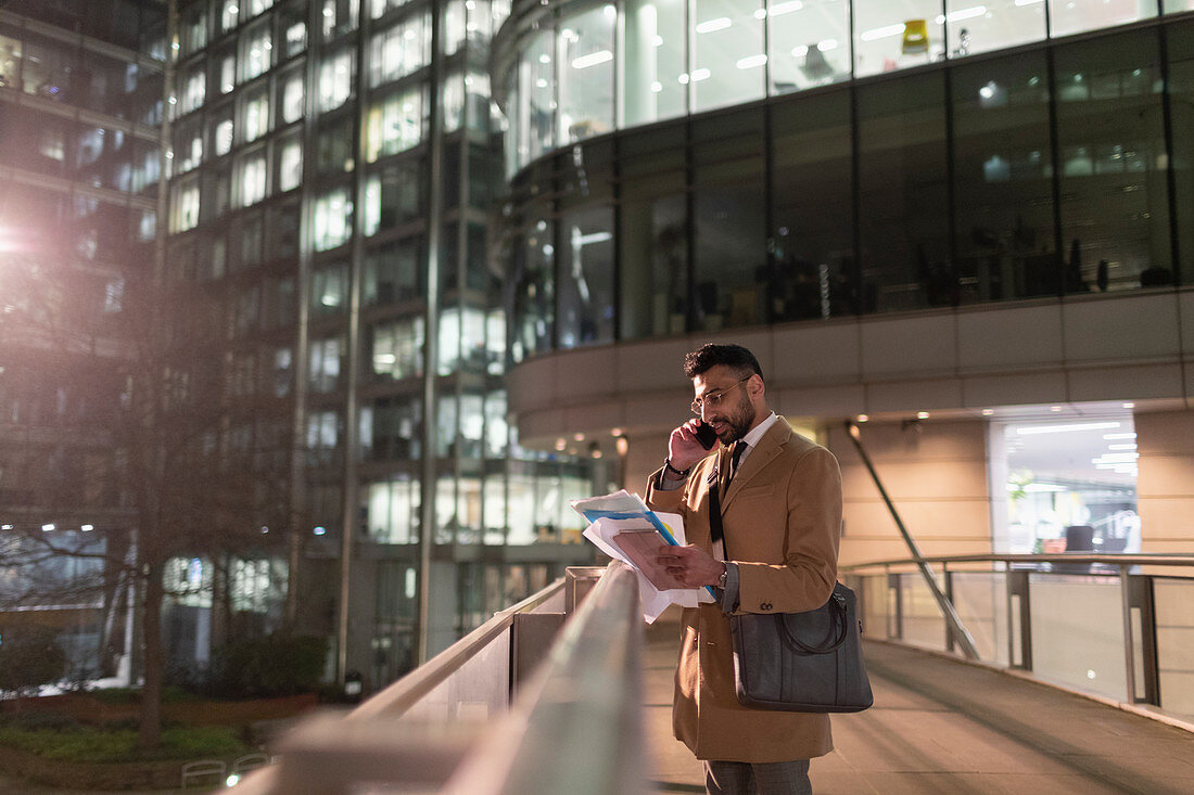 Businessman reading paperwork on bridge at night