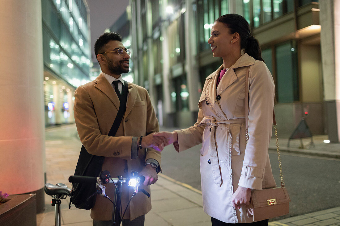 Business people with bicycle handshaking at night
