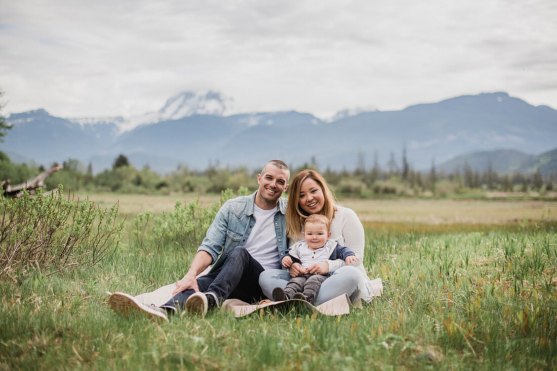 Parents and baby son sitting in rural field