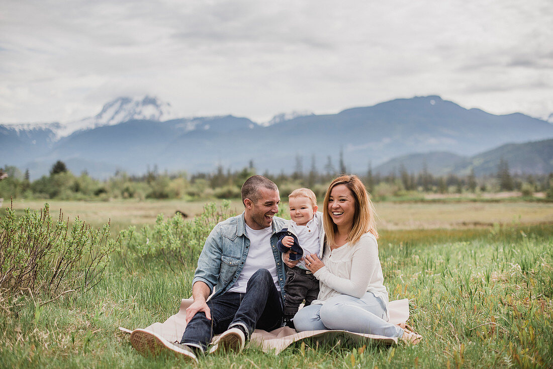 Parents and baby son sitting in rural field