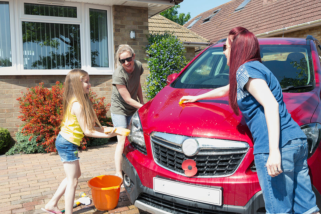 Lesbian couple and daughter washing car