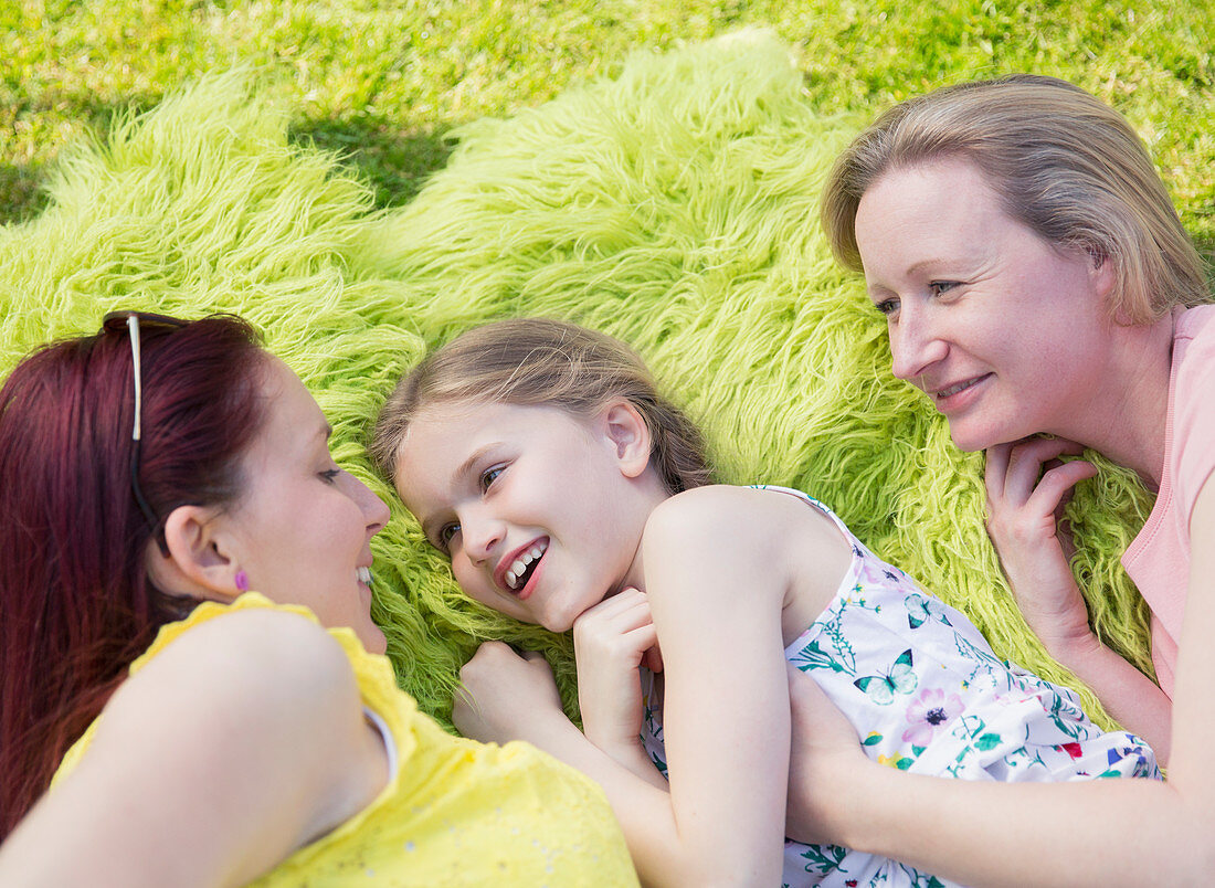 Lesbian couple and daughter laying in grass