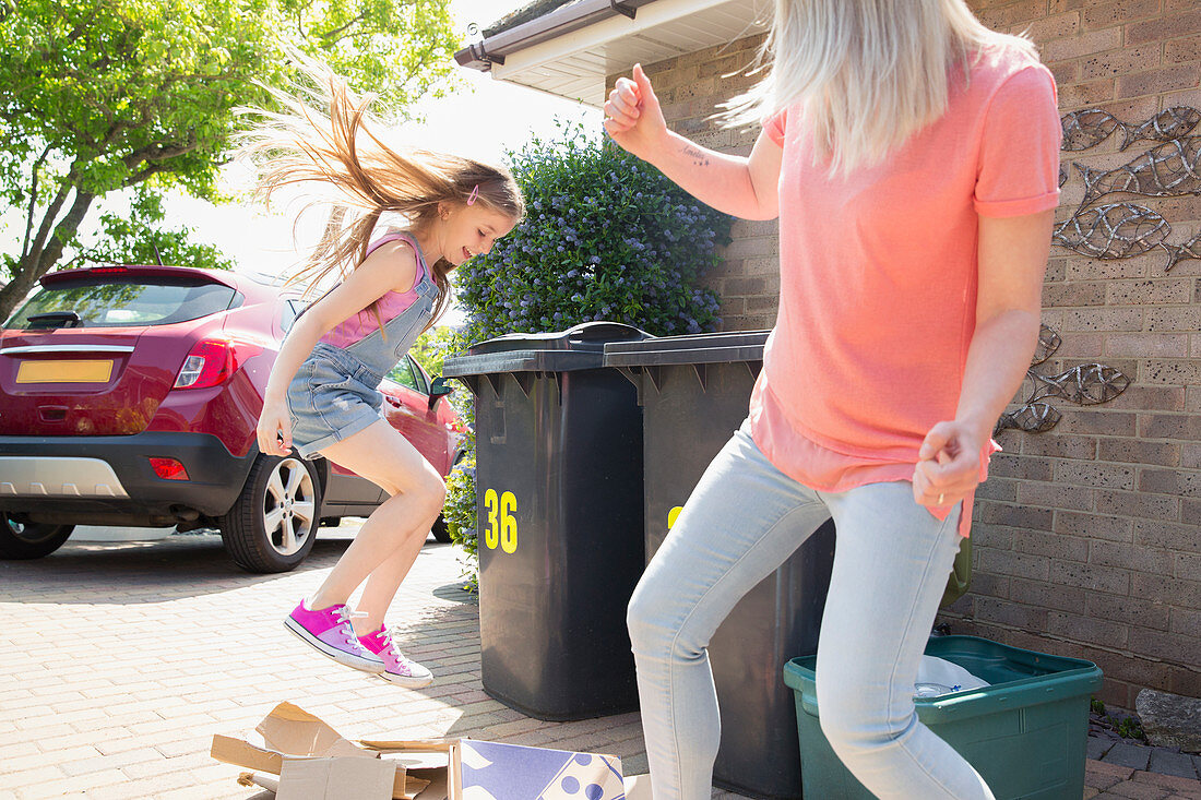 Mother and playful daughter recycling cardboard