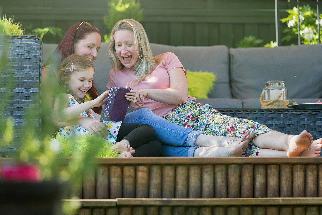 Lesbian couple and daughter using digital tablet