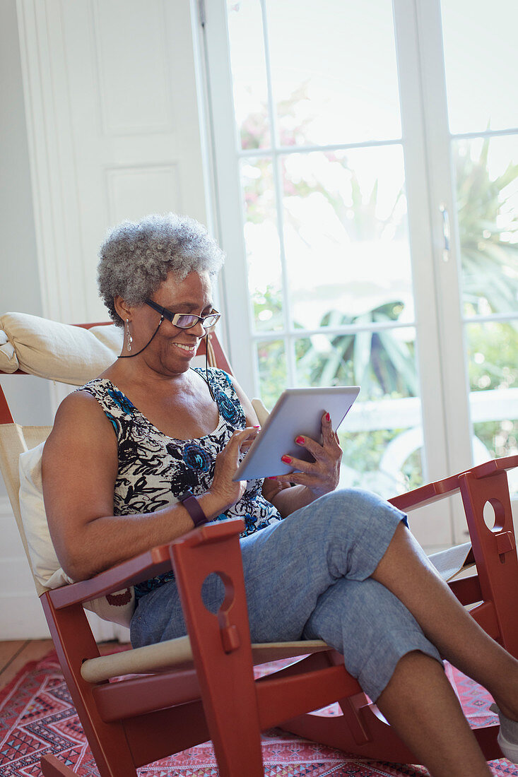 Senior woman using digital tablet in rocking chair