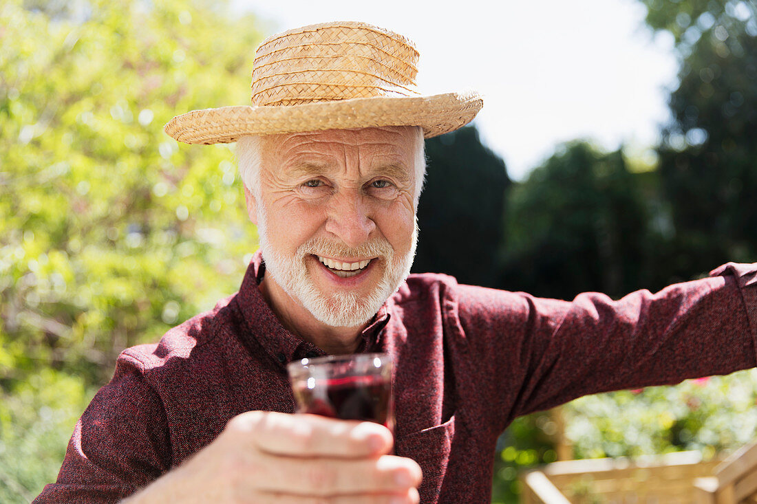 Senior man drinking red wine in garden