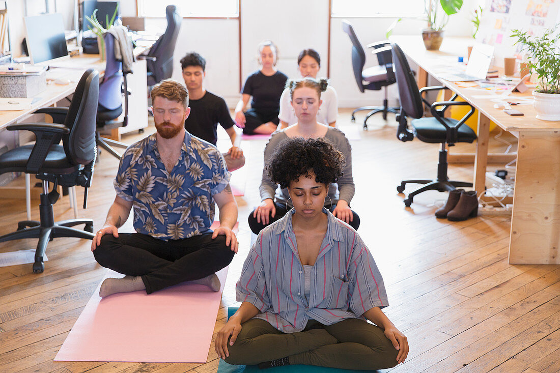 Creative business people meditating in office