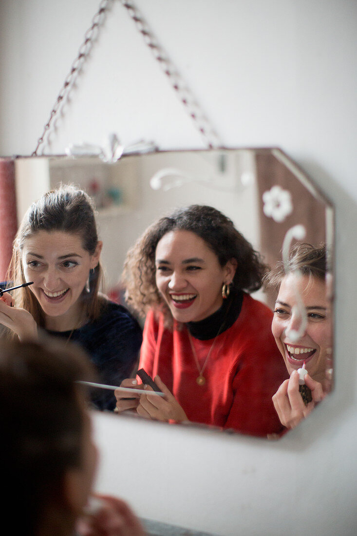 Young women friends applying makeup