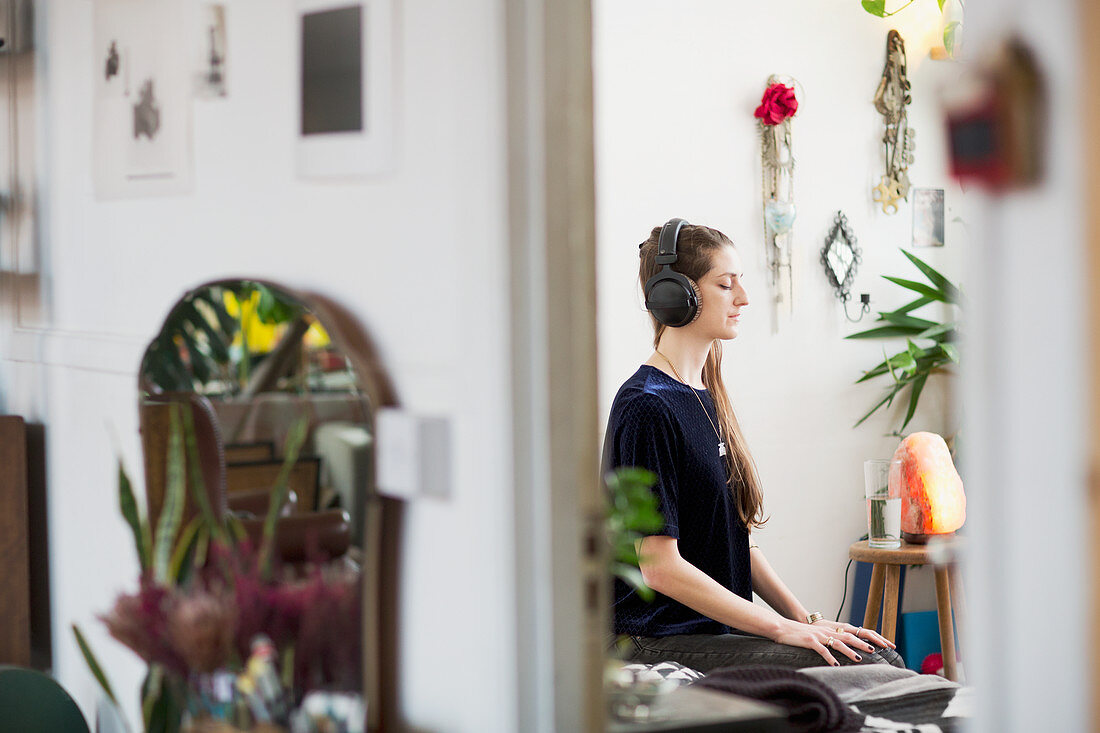 Serene young woman meditating with headphones