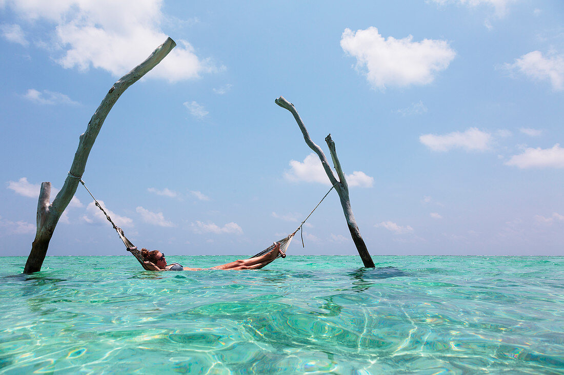 Woman laying in hammock over tranquil ocean