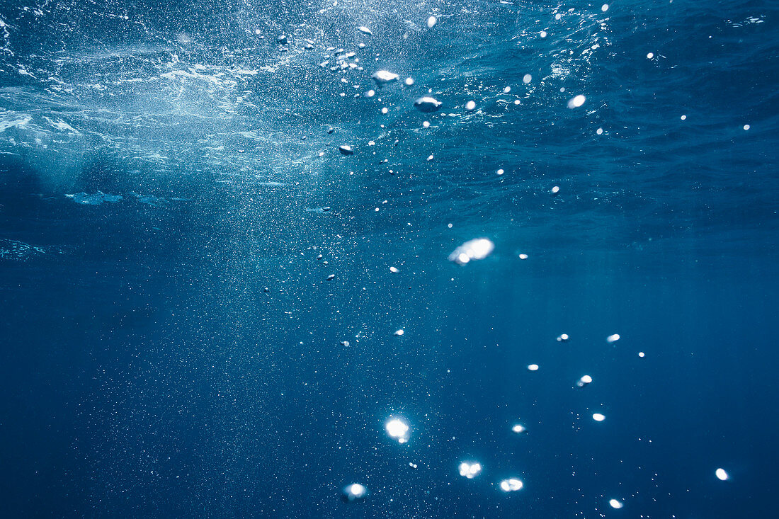 Sunlight and bubbles underwater in blue ocean