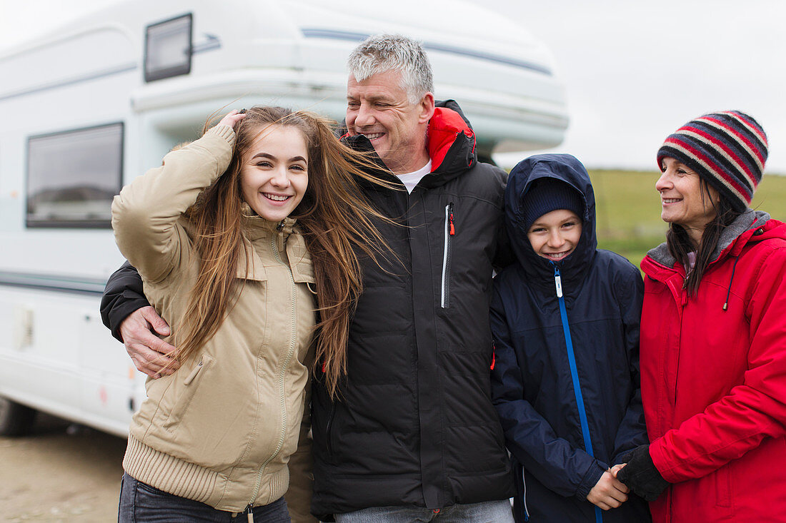 Family in warm clothing outside motor home