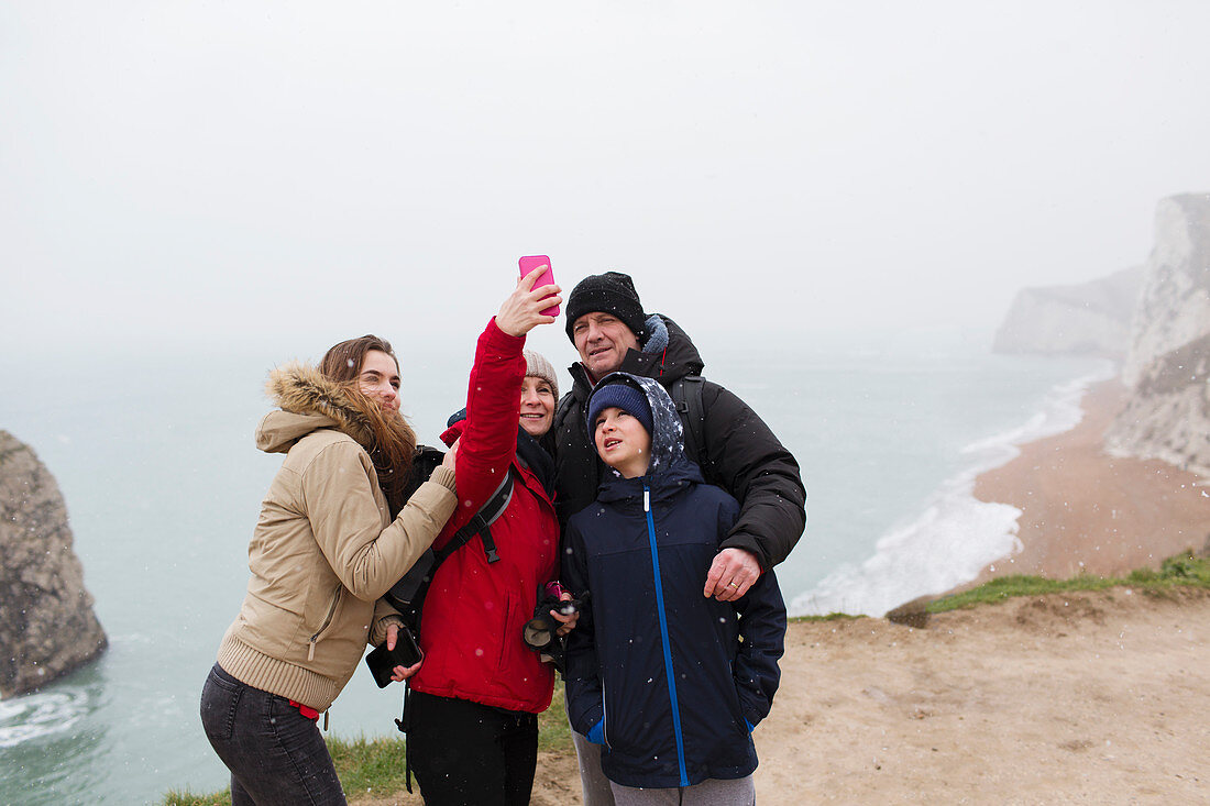 Family taking selfie on cliff overlooking ocean
