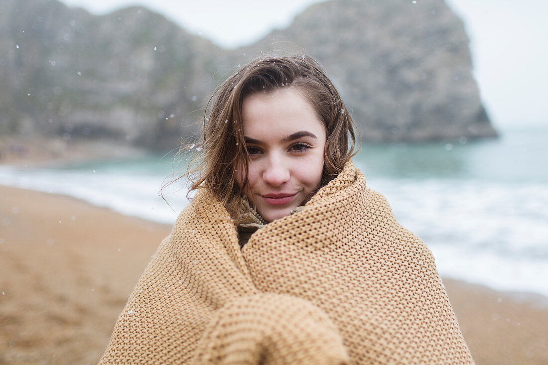 Portrait girl wrapped in blanket on beach