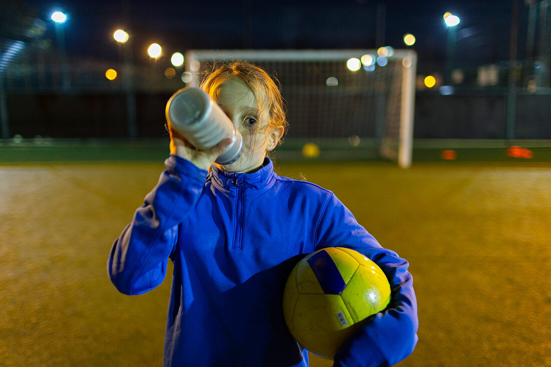 Girl soccer player taking a break, drinking water