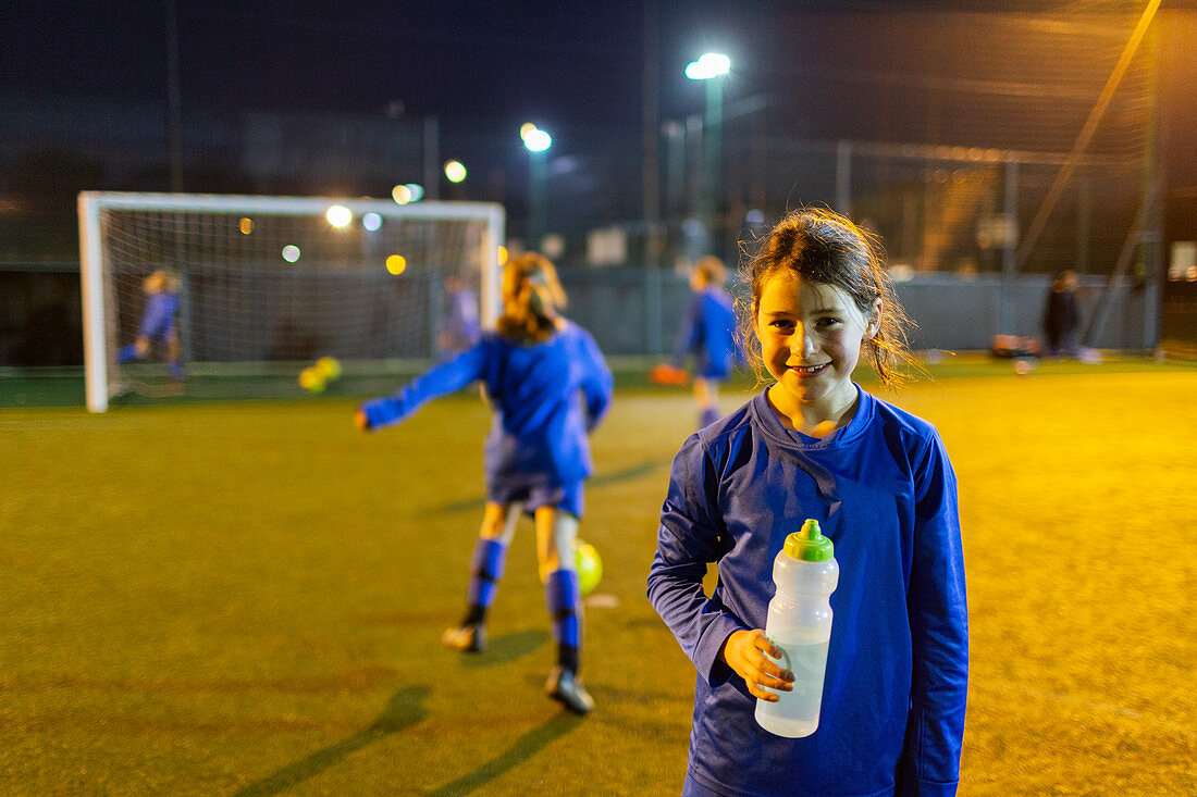 Portrait smiling girl soccer player drinking water