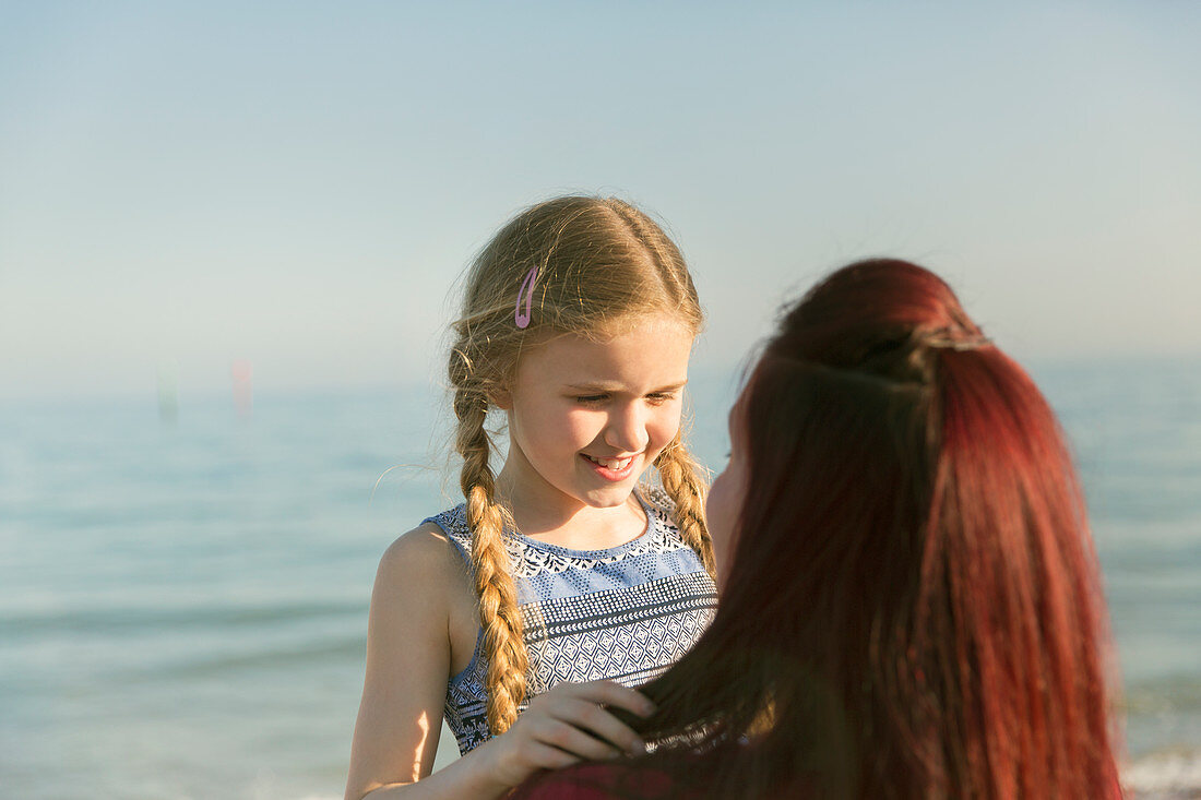 Mother holding daughter on ocean beach