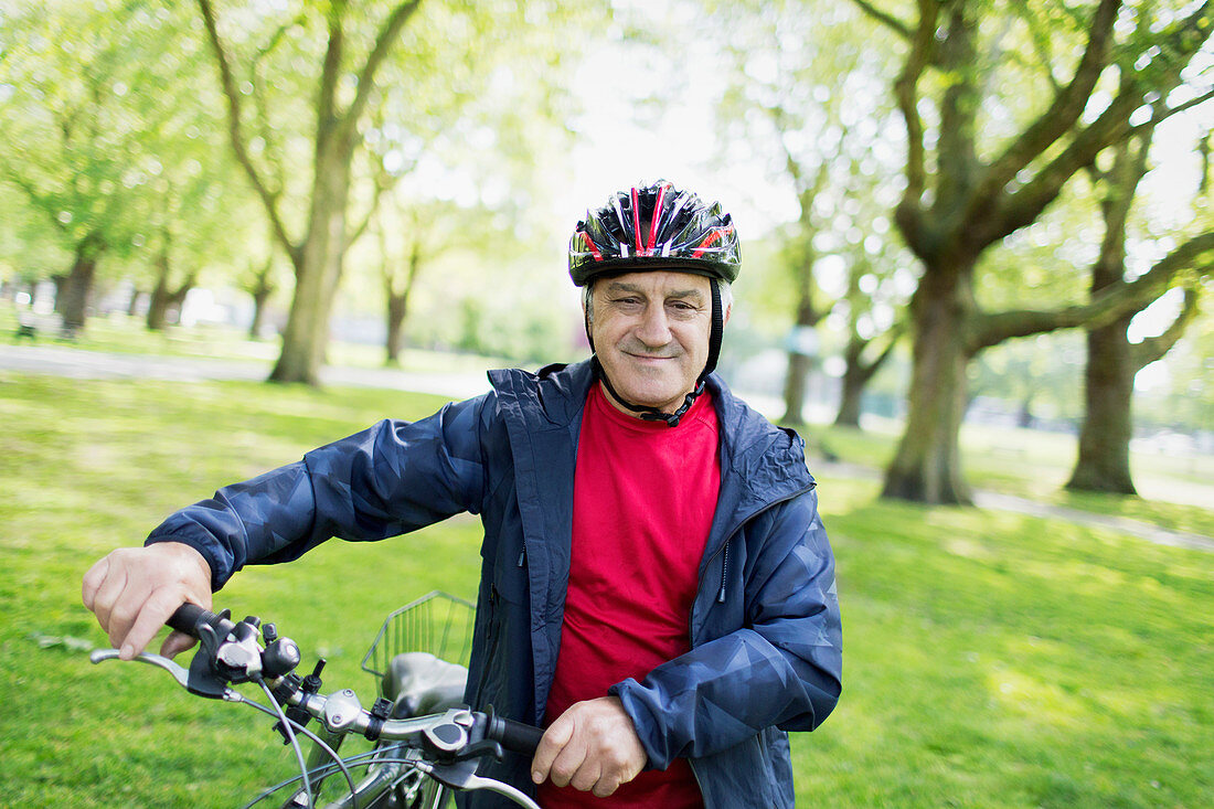 Portrait active senior man riding bike in park