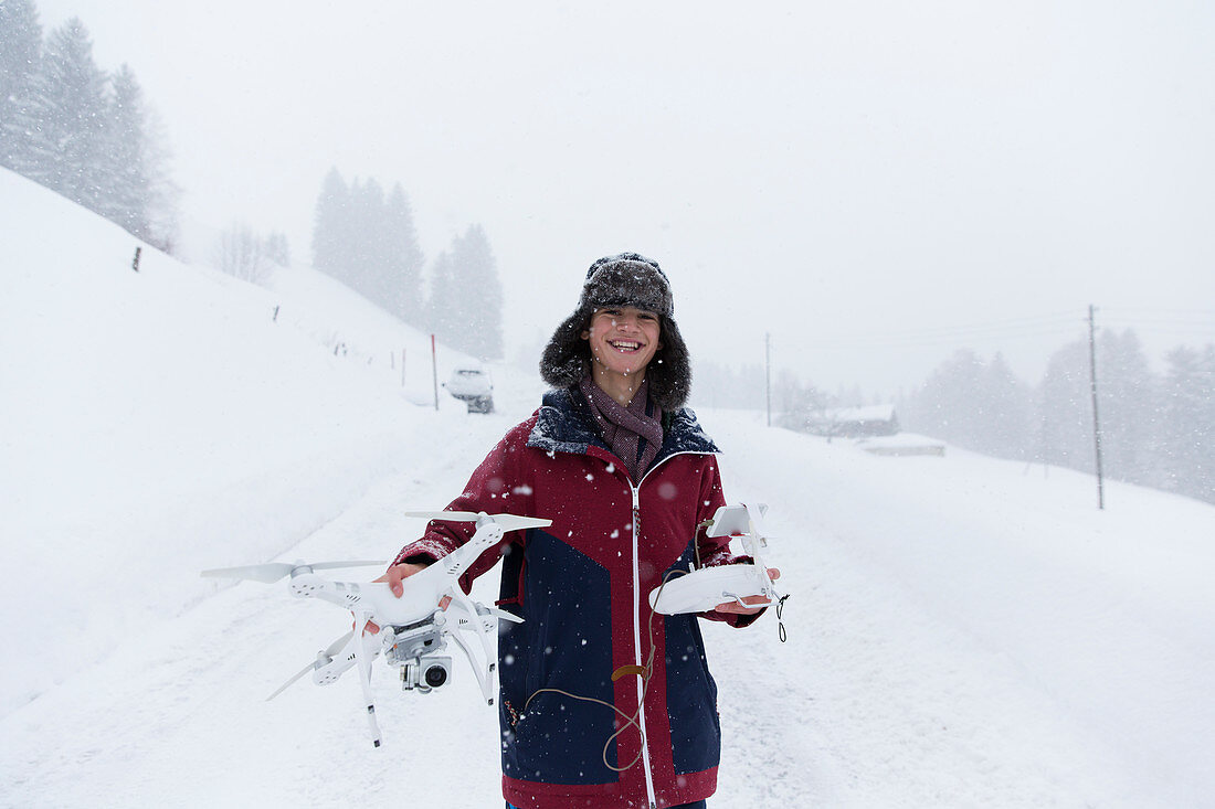 Portrait boy with drone in snowy landscape