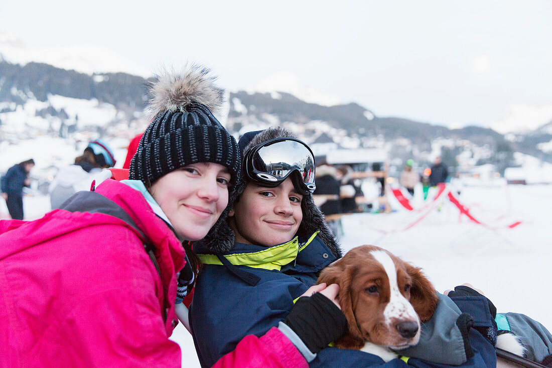 Portrait brother and sister with dog on ski slope