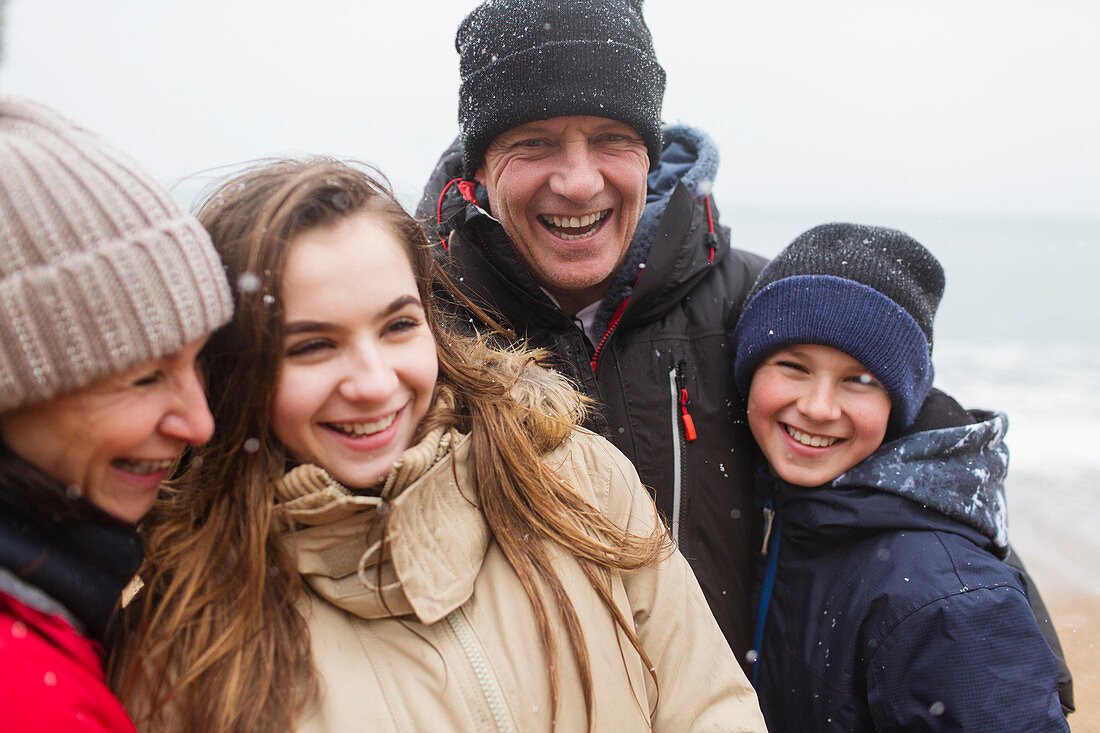 Snow falling over happy family in warm clothing