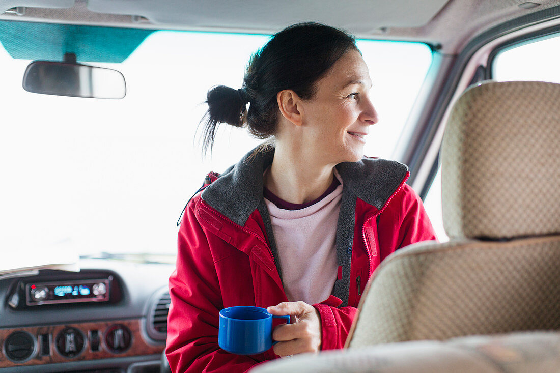 Smiling woman drinking coffee in motor home