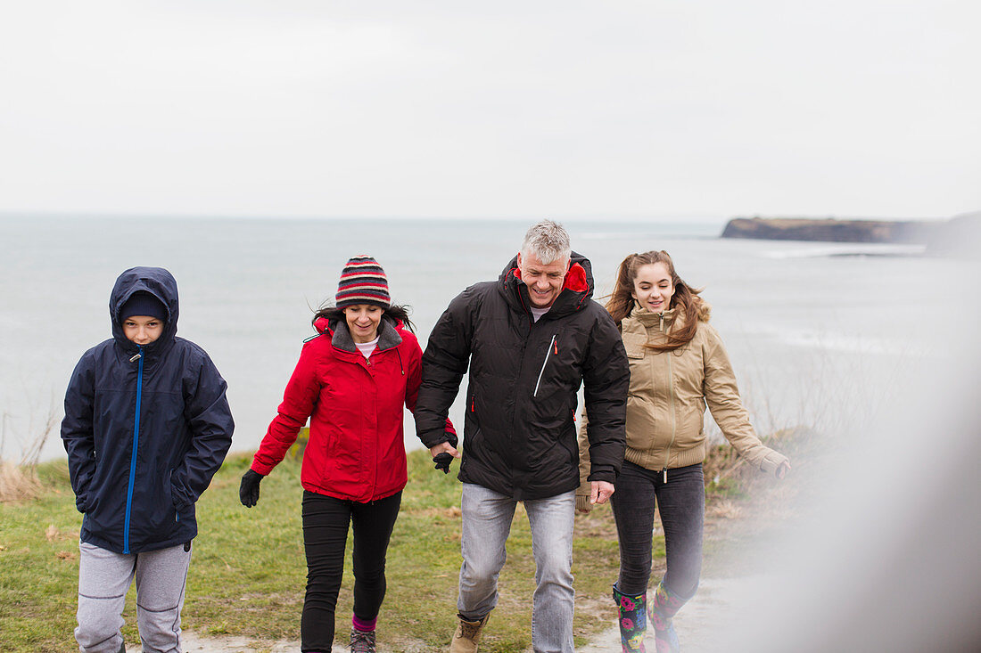 Family in warm clothing on cliff overlooking ocean
