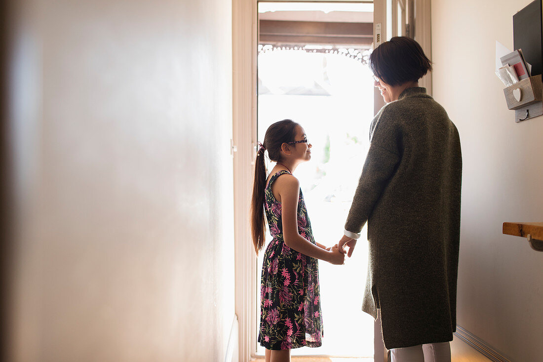 Mother and daughter holding hands in doorway