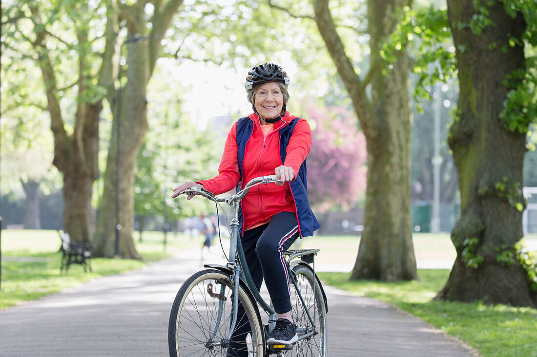 Portrait active senior woman riding bike in park