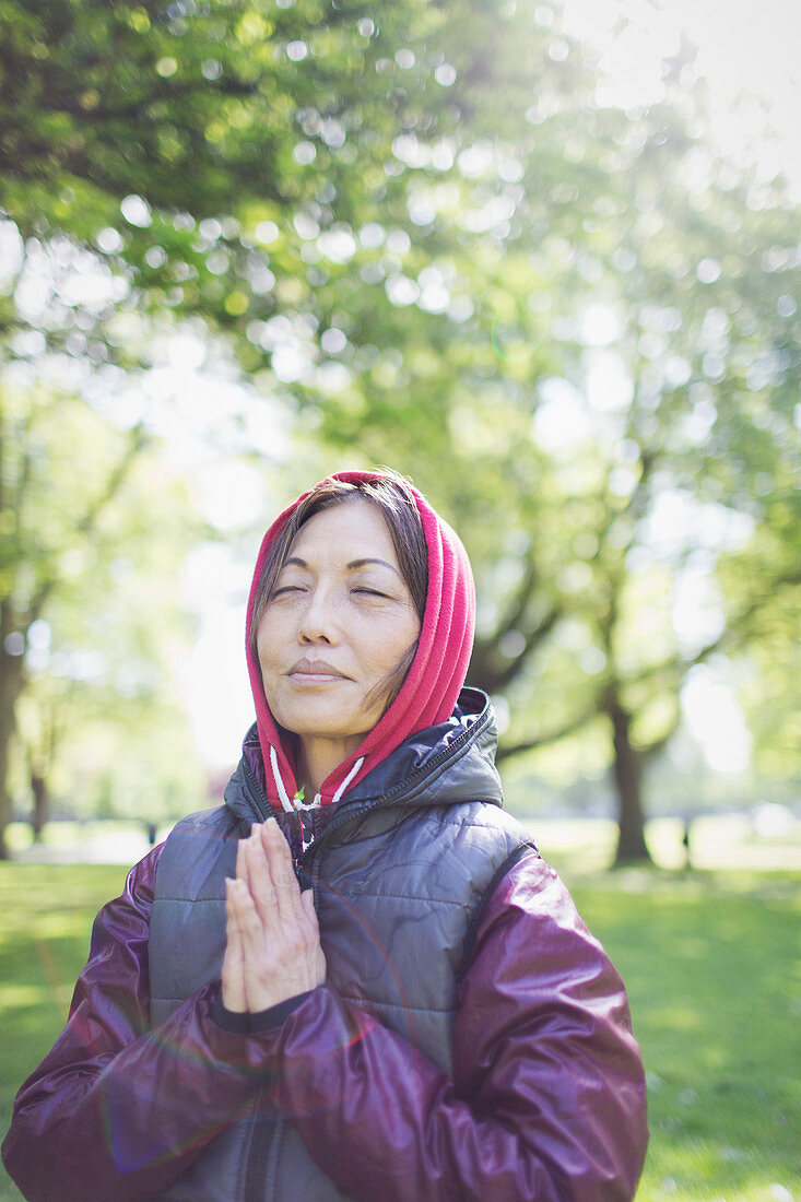 Serene active senior woman meditating in park