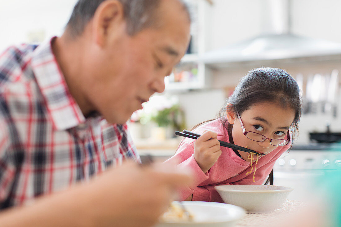 Grandfather and granddaughter eating noodles