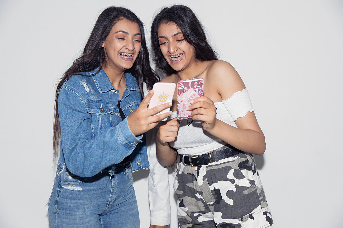 Teenage twin sisters using smart phones