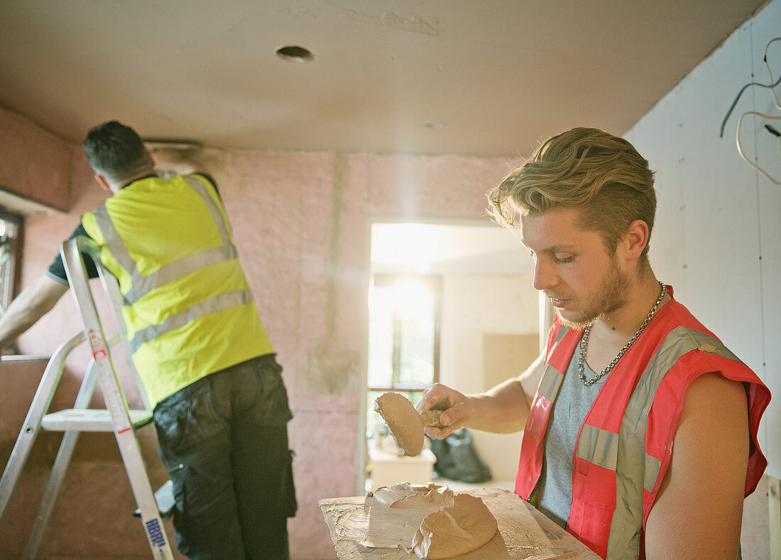 Construction workers plastering in house