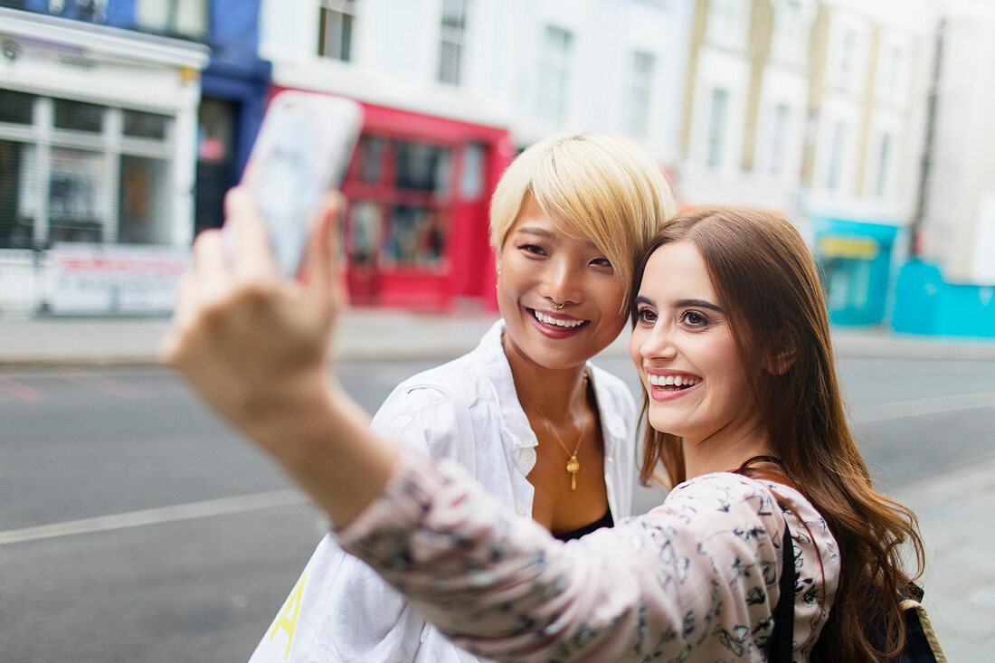 Young women friends taking selfie on urban street