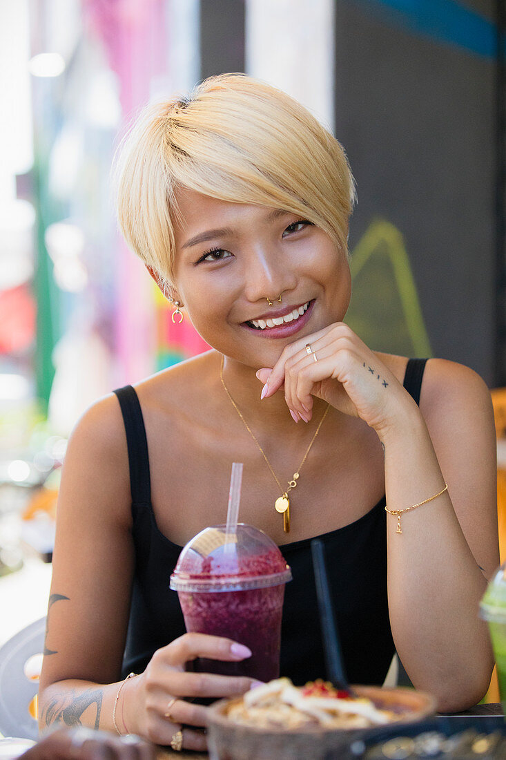 Young woman drinking smoothie at sidewalk cafe