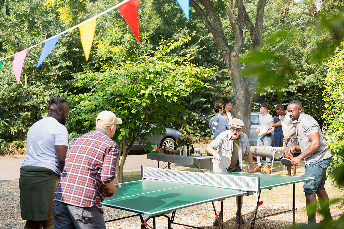 Male friends playing ping pong in back yard