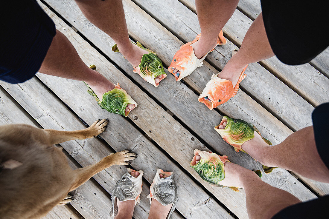 Friends wearing humorous fish slippers on dock