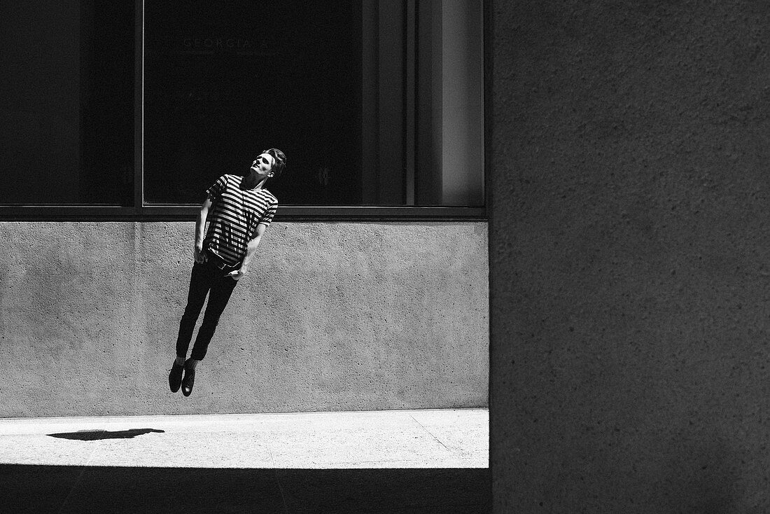 Young man jumping on urban sidewalk