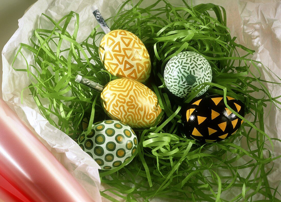 Colourful Easter eggs & banknote rolls in artificial grass